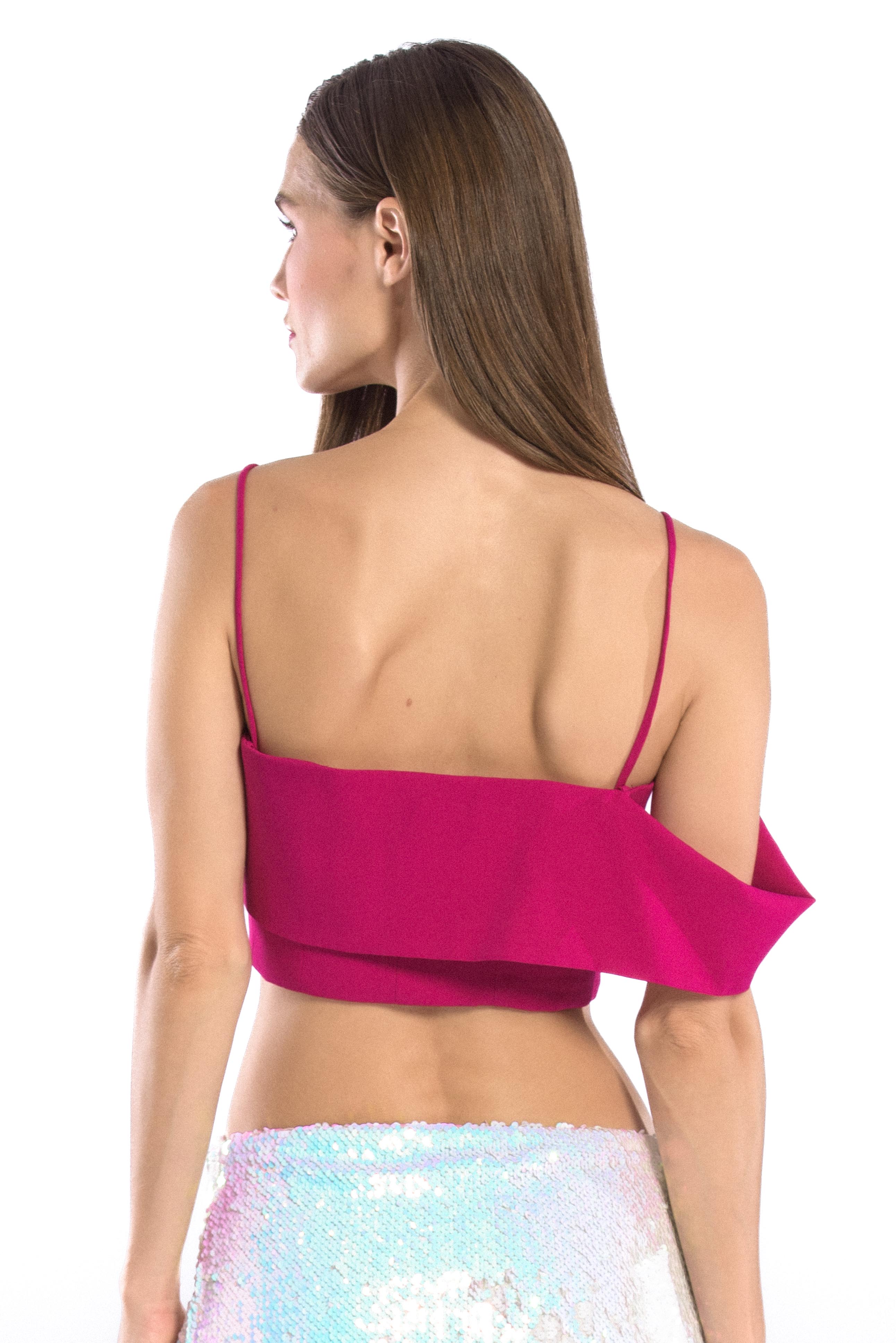 Back shot of model wearing asymmetric off shoulder crop top in hot pink or fuchsia color and iridescent sequins mini skirt