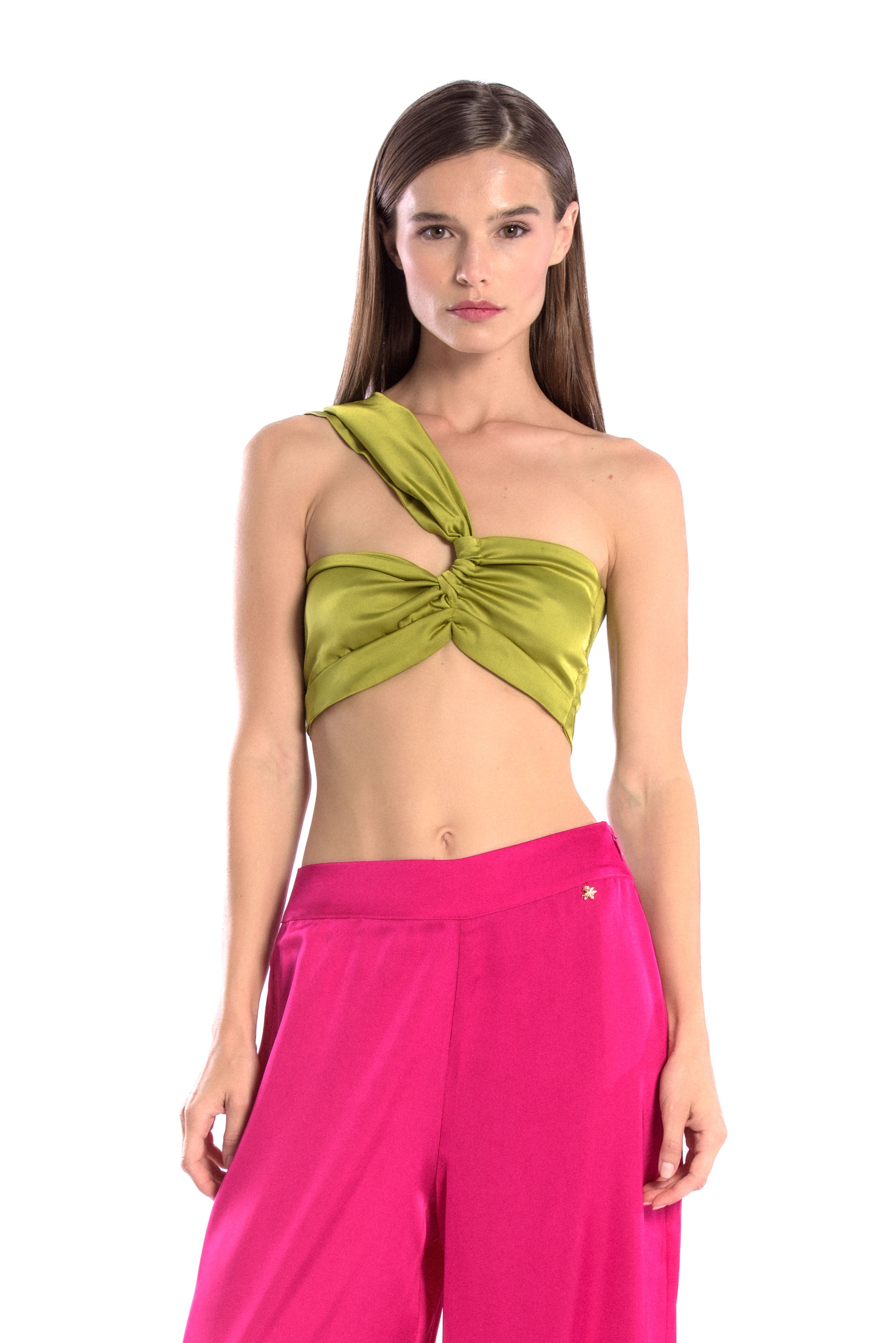 Model wearing a silk cross shoulder crop top in olive with back firefly logo golden zipper and silk pants in hot pink or fuchsia color with a firefly golden charm