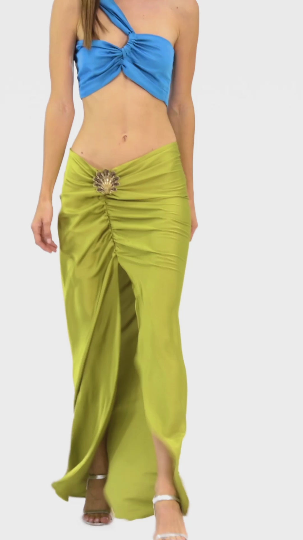 Video of model wearing a silk cross shoulder crop top in orange with back firefly logo golden zipper and silk pants in blue color with a firefly golden charm